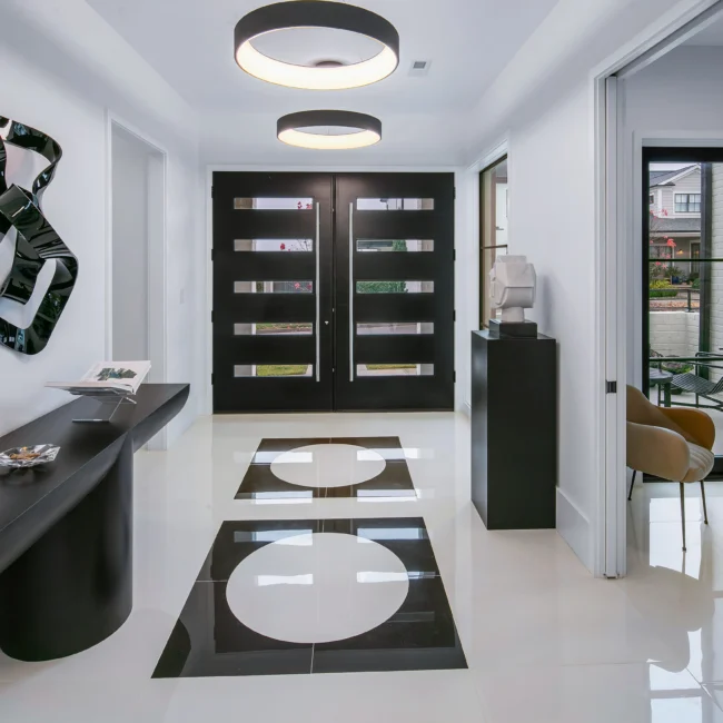 Foyer with black front doors, circular floor medallion and pendant light in Urban Oasis, a custom home by Mike Stevens Homes