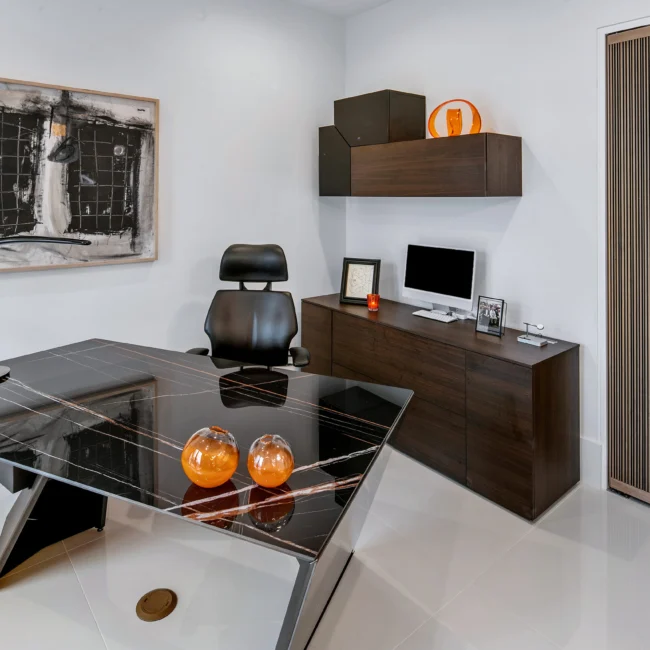 Home office with black glass desk, orange accents and wall-hung walnut cabinet in Urban Oasis by Mike Stevens Homes