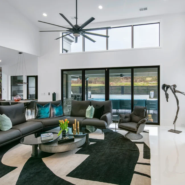Living room with black leather sofa, sliding glass doors and tall ceilings in Urban Oasis by Mike Stevens Homes