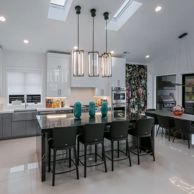Kitchen with black island, teal vases and gray cabinets under pendant lights in Urban Oasis by Mike Stevens Homes