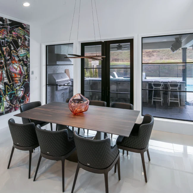 Dining room with walnut table, black upholstered chairs and glass doors to patio in Urban Oasis by Mike Stevens Homes