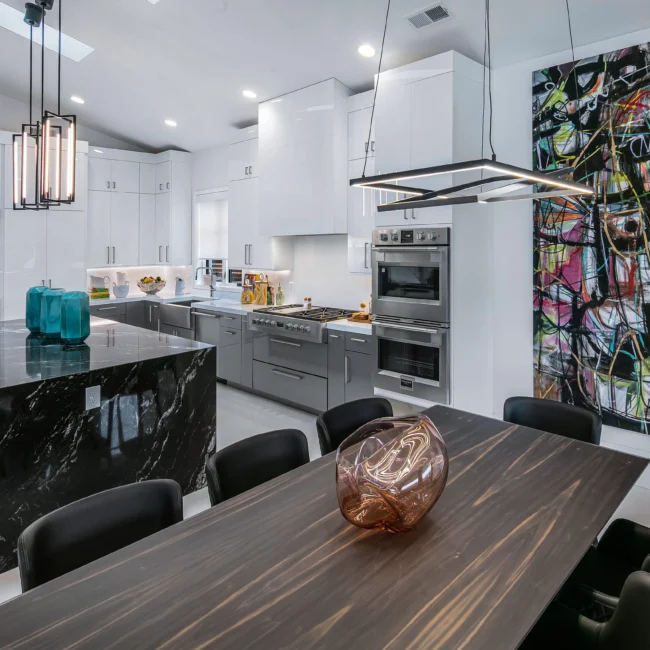 Dining table beside black marble island and colorful art wall in Urban Oasis by Mike Stevens Homes