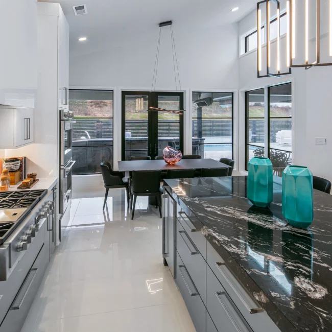Kitchen with dark marble island, black-framed windows and white cabinets in Urban Oasis by Mike Stevens Homes