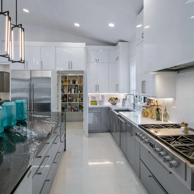 Kitchen with gas range, stainless fridge and white glossy cabinets in Urban Oasis by Mike Stevens Homes