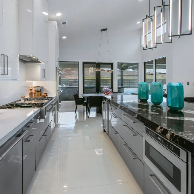 Kitchen with black marble island, range and tall glass-front pendants in Urban Oasis by Mike Stevens Homes