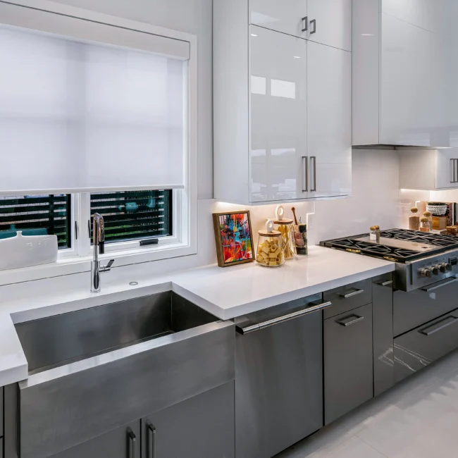 Farmhouse sink under window with gray cabinetry and white quartz counters in Urban Oasis by Mike Stevens Homes