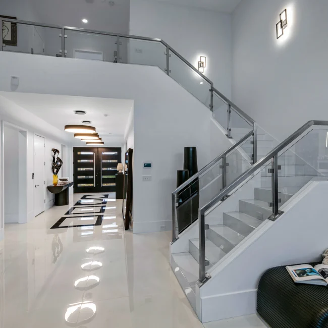 Hallway with glass-rail staircase and recessed floor lights in Urban Oasis by Mike Stevens Homes