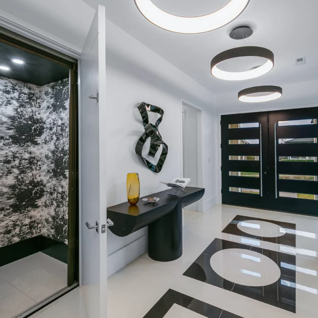 Entry with black console table, abstract wall sculpture and double doors in Urban Oasis by Mike Stevens Homes