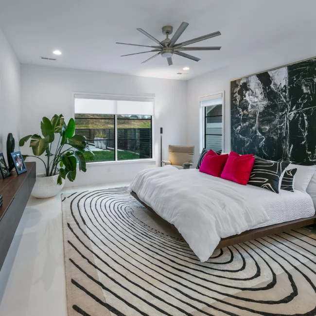 Primary bedroom with black-and-white curved rug and dark marble accent wall in Urban Oasis by Mike Stevens Homes