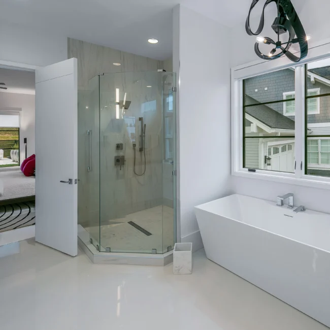 Bath with frameless glass shower, freestanding tub and bedroom glimpse in Urban Oasis by Mike Stevens Homes