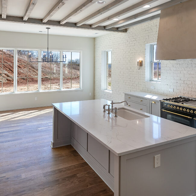 Kitchen island with quartz counter and wide window views in Minimalist French Farmhouse, a custom home by Mike Stevens Homes