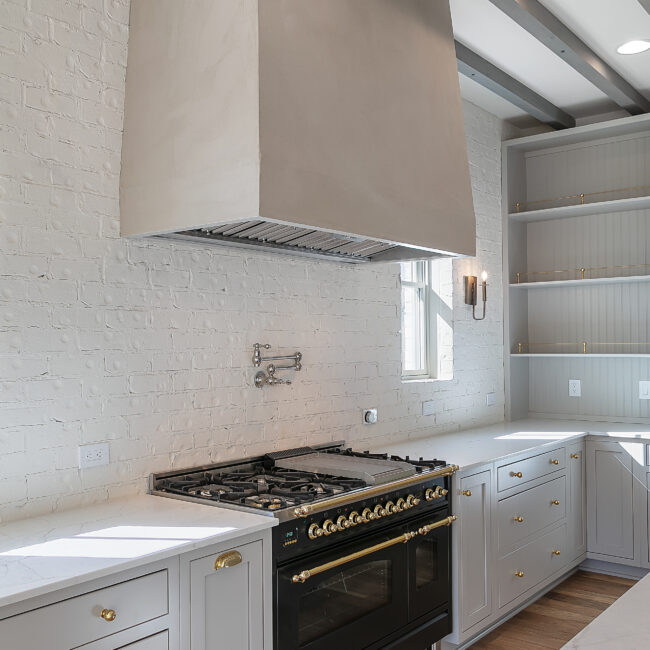 Plaster range hood above black range and open shelves in Minimalist French Farmhouse, a custom home by Mike Stevens Homes