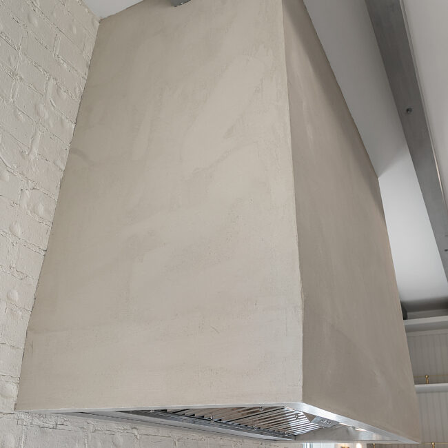 Close-up of curved plaster range hood in Minimalist French Farmhouse, a custom home by Mike Stevens Homes