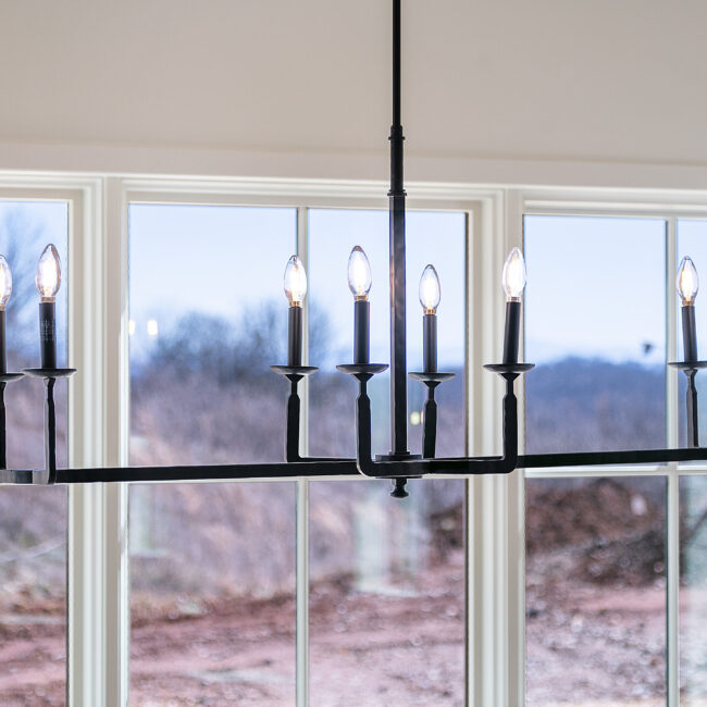 Black chandelier in front of large windows in Minimalist French Farmhouse, a custom home by Mike Stevens Homes