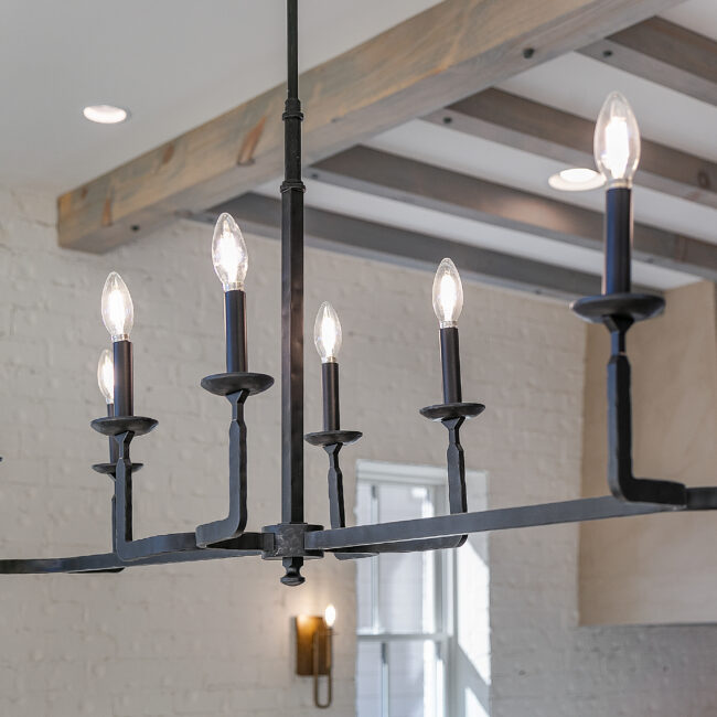 Black iron chandelier under exposed wood beams in Minimalist French Farmhouse, a custom home by Mike Stevens Homes