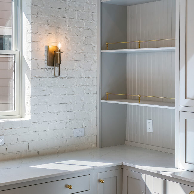 Built-in shelving with brass accents and quartz counter in Minimalist French Farmhouse, a custom home by Mike Stevens Homes