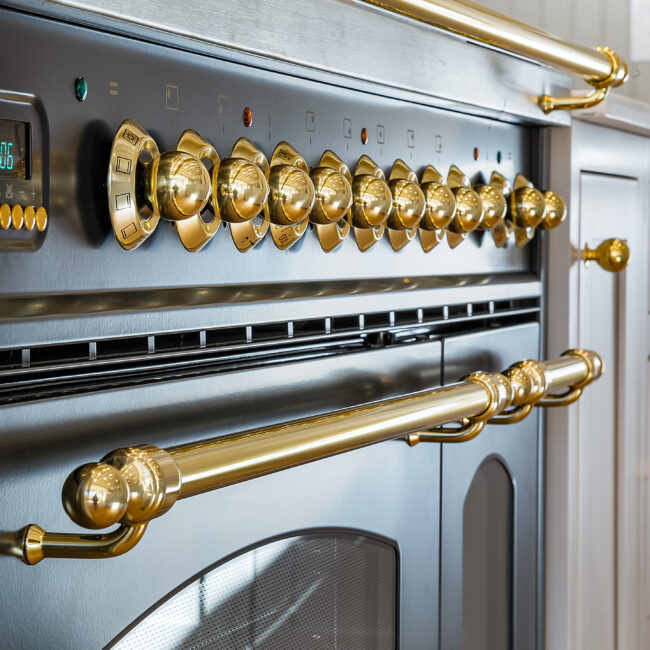 Black range with brass knobs and brass handle rail in Minimalist French Farmhouse, a custom home by Mike Stevens Homes