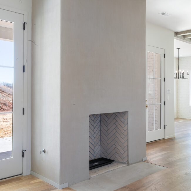 Plaster fireplace with herringbone firebox and doors in Minimalist French Farmhouse, a custom home by Mike Stevens Homes