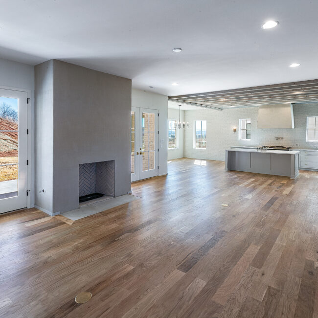 Open great room with fireplace and wood floors in Minimalist French Farmhouse, a custom home by Mike Stevens Homes