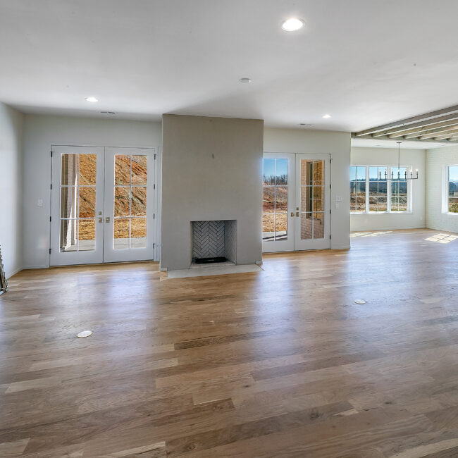 Great room with French doors and plaster fireplace in Minimalist French Farmhouse, a custom home by Mike Stevens Homes