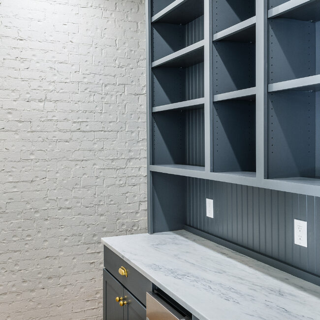 Built-in slate-blue shelving and quartz desk nook in Minimalist French Farmhouse, a custom home by Mike Stevens Homes