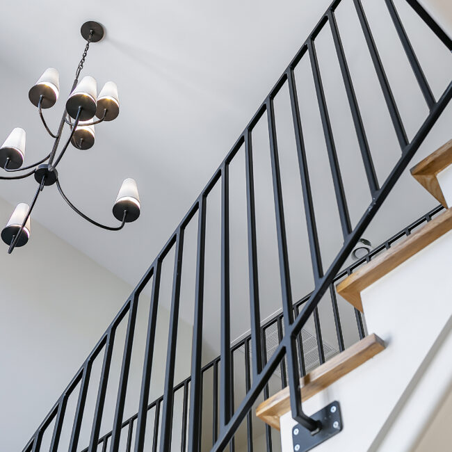 Close-up of black iron stair railing and wood treads in Minimalist French Farmhouse, a custom home by Mike Stevens Homes