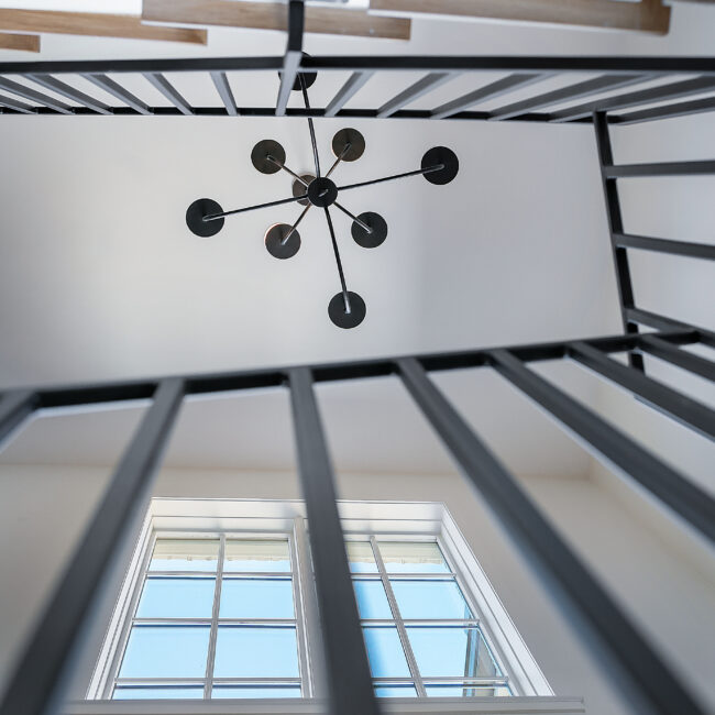 Looking up at black iron railing and window above in Minimalist French Farmhouse, a custom home by Mike Stevens Homes