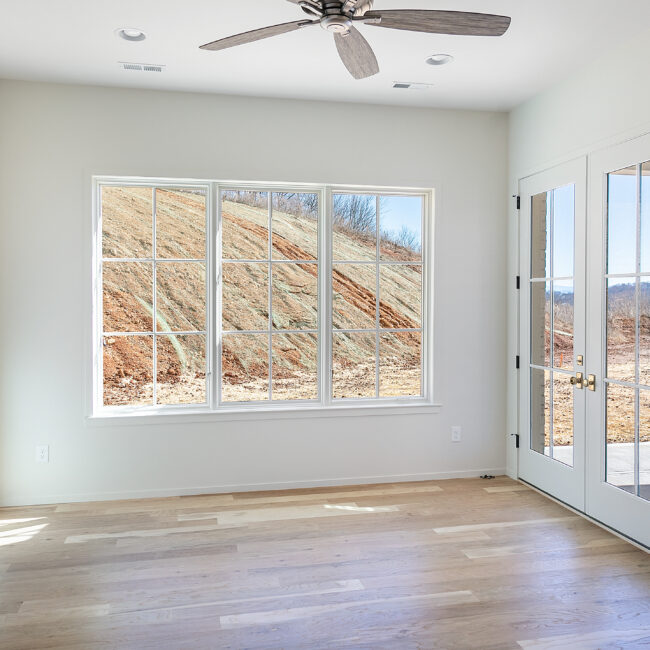 Bedroom with large window overlooking hillside in Minimalist French Farmhouse, a custom home by Mike Stevens Homes