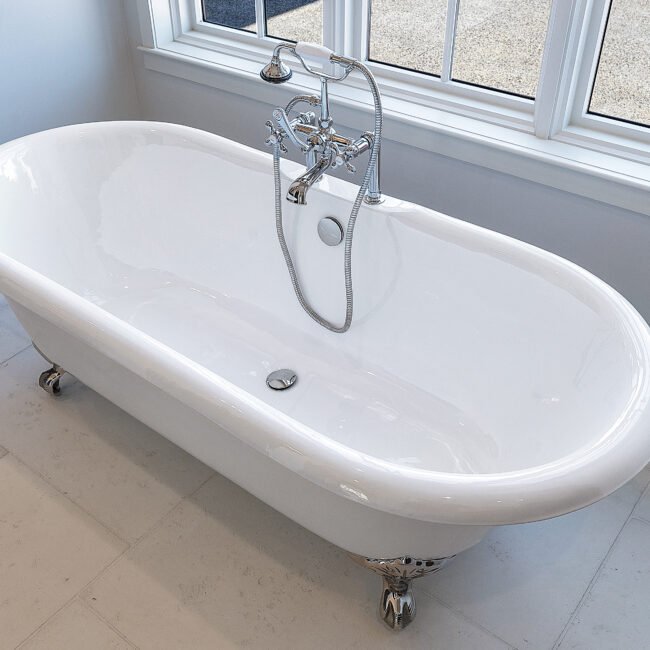 Freestanding clawfoot tub with wall-mounted fixture in Minimalist French Farmhouse, a custom home by Mike Stevens Homes