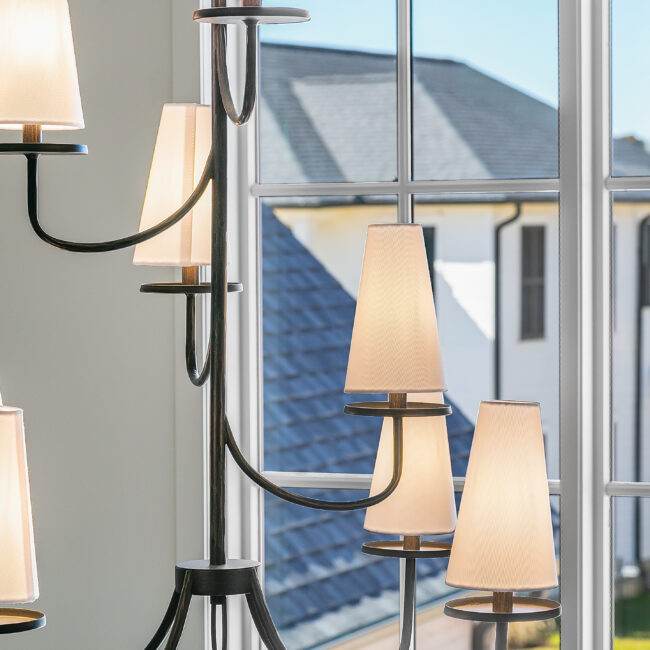 Chandelier with fabric shades in front of tall window in Minimalist French Farmhouse, a custom home by Mike Stevens Homes