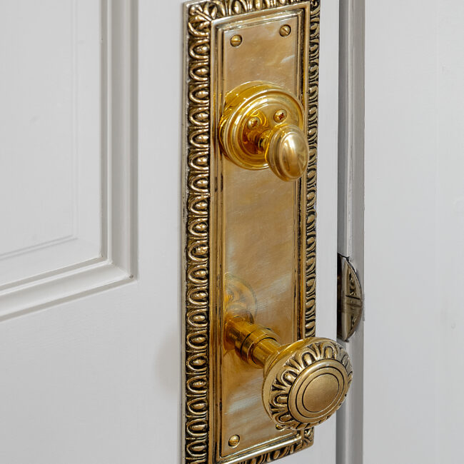 Close-up of ornate brass door handle on white door in Minimalist French Farmhouse, a custom home by Mike Stevens Homes