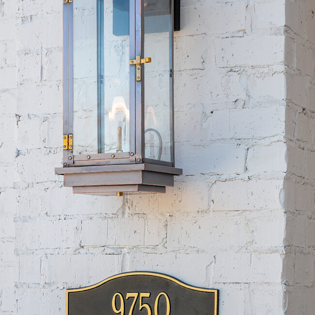 Lantern sconce on whitewashed brick exterior wall in Minimalist French Farmhouse, a custom home by Mike Stevens Homes