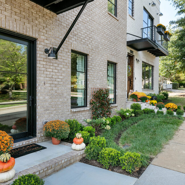 Brick exterior with black balcony railing and landscaped front walk in Urban Loft, a custom home by Mike Stevens Homes