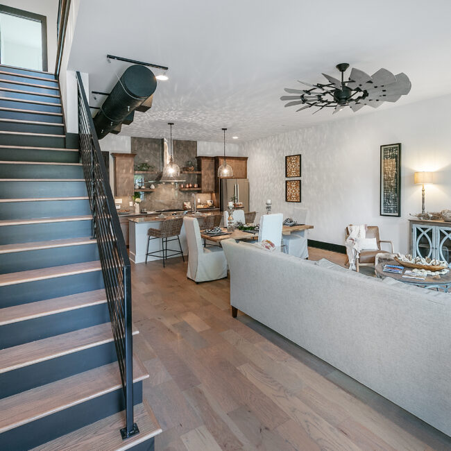 Open-concept kitchen and dining room beside a blue-stained staircase in Urban Loft, a custom home by Mike Stevens Homes