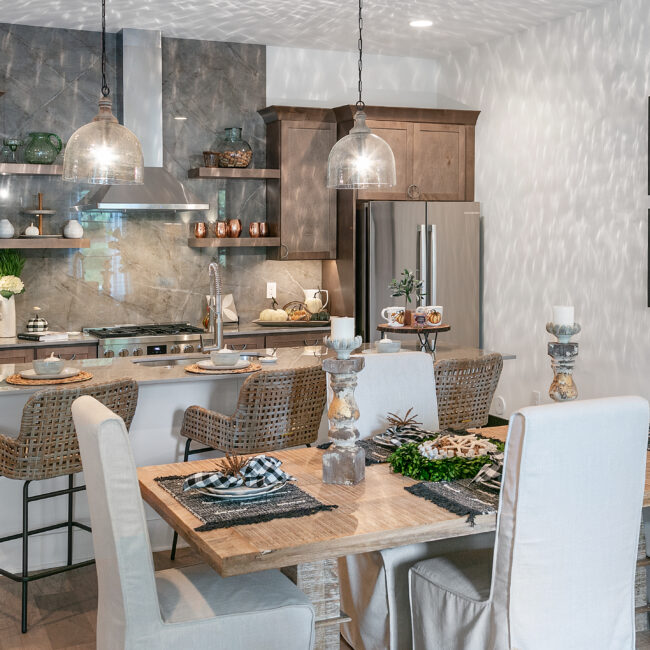 Kitchen dining table with wicker chairs and pendant lights in Urban Loft, a custom home by Mike Stevens Homes