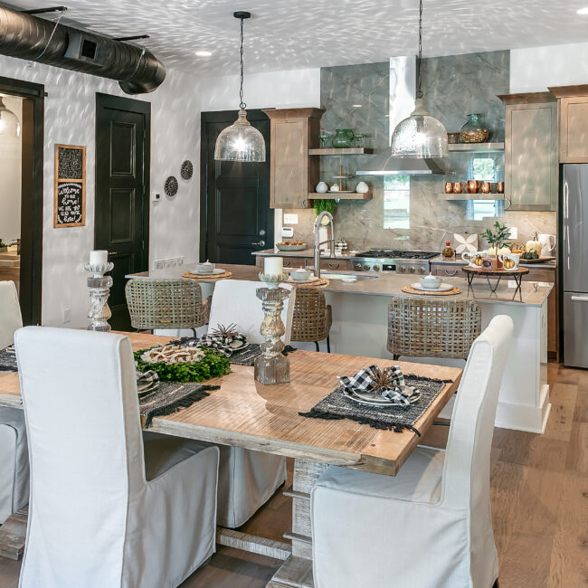 Dining table with slipcovered chairs and dark cabinetry beyond in Urban Loft, a custom home by Mike Stevens Homes