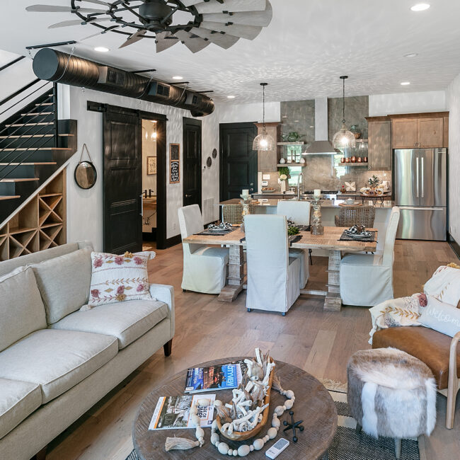Living room with light gray sofa, round coffee table and open kitchen in Urban Loft, a custom home by Mike Stevens Homes