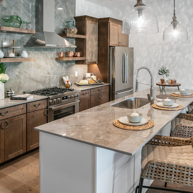 Kitchen island with farmhouse sink, pendant lights and wicker barstools in Urban Loft, a custom home by Mike Stevens Homes
