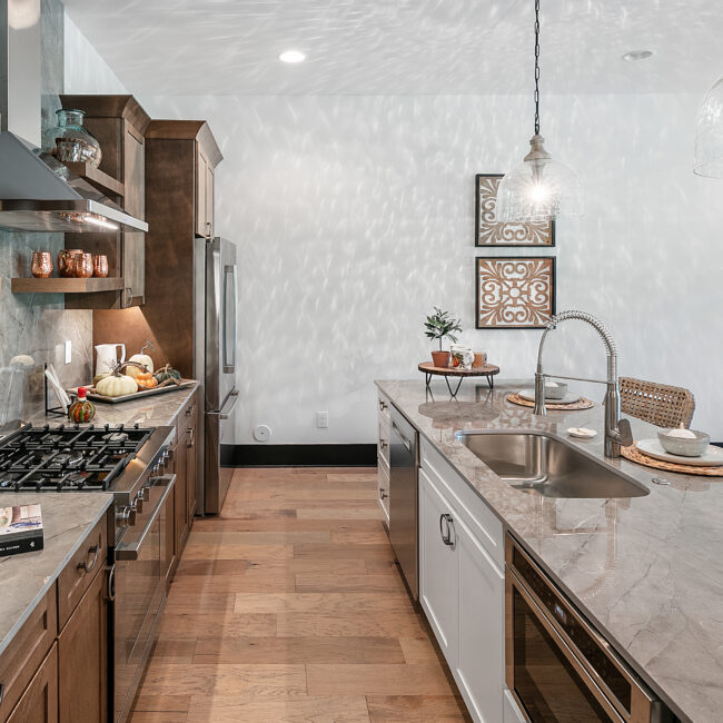 Galley kitchen with stainless refrigerator and wood-look tile floor in Urban Loft, a custom home by Mike Stevens Homes