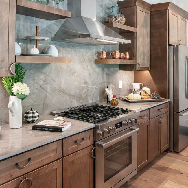 Kitchen with gray marble backsplash, wood cabinets and hood vent in Urban Loft, a custom home by Mike Stevens Homes