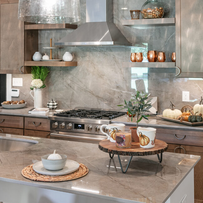 Kitchen island with rustic wood tray, gas range and marble backsplash in Urban Loft, a custom home by Mike Stevens Homes