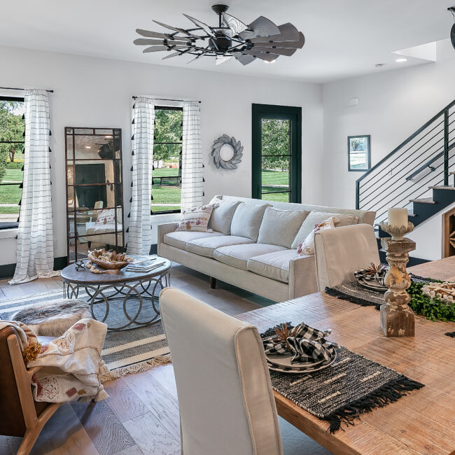 Living room with gray sofa, staircase and wood-framed windows in Urban Loft, a custom home by Mike Stevens Homes