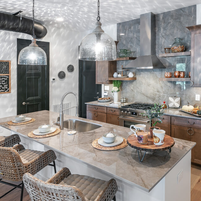 Kitchen island with pendant lights, wicker stools and range in Urban Loft, a custom home by Mike Stevens Homes