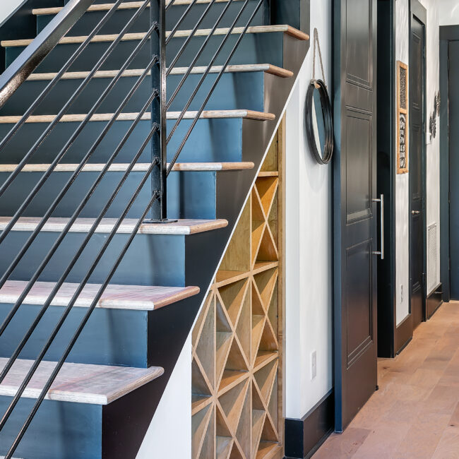 Staircase with wood treads, black railing and built-in wine rack in Urban Loft, a custom home by Mike Stevens Homes