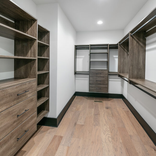 Walk-in closet with wood cabinetry, drawers and hanging rods in Urban Loft, a custom home by Mike Stevens Homes