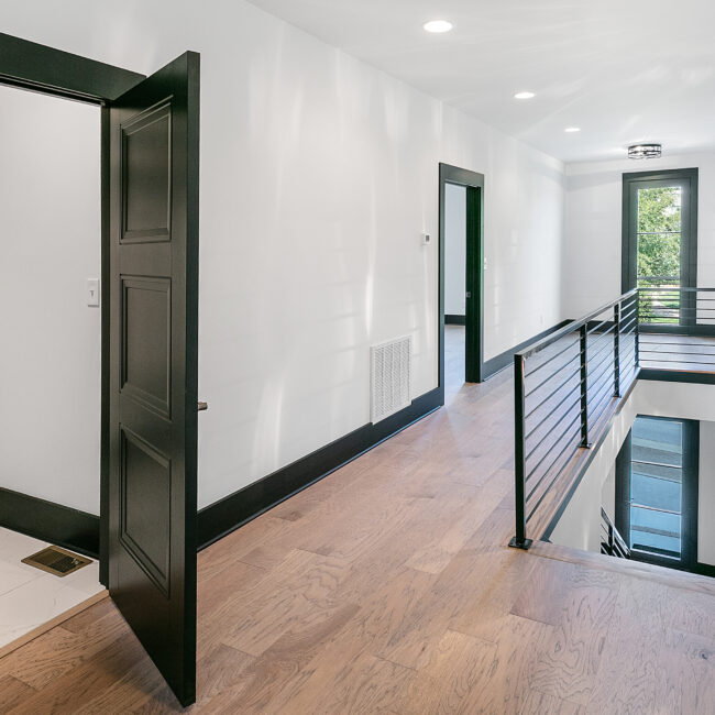 Hallway with black cable railing and hardwood floors in Urban Loft, a custom home by Mike Stevens Homes