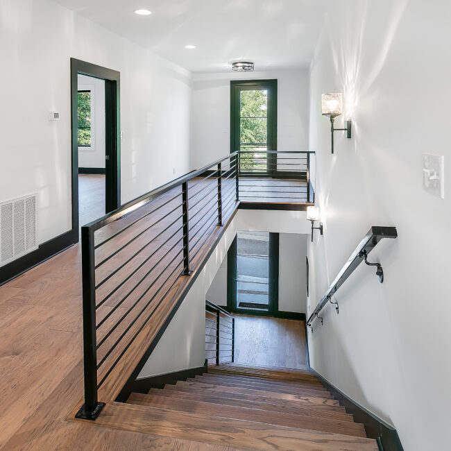 Staircase with black cable railing overlooking the foyer in Urban Loft, a custom home by Mike Stevens Homes