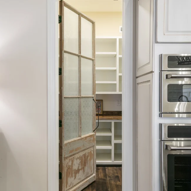 Walk-in pantry with weathered wood door and built-in shelves in European Villa, a custom home by Mike Stevens Homes
