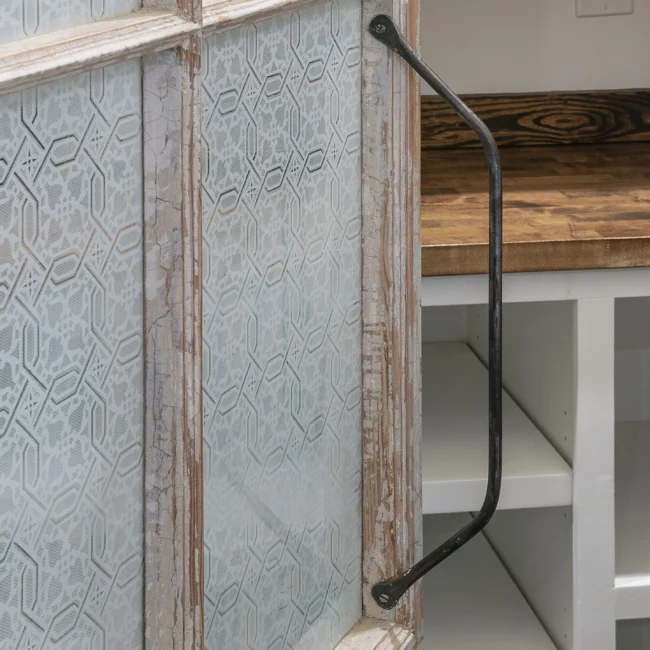 Close-up of textured tile panel, black iron pull and wood shelf in European Villa, a custom home by Mike Stevens Homes
