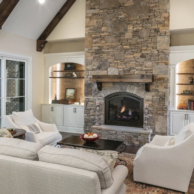 Stone fireplace with wood mantel flanked by built-in niches in European Villa, a custom home by Mike Stevens Homes